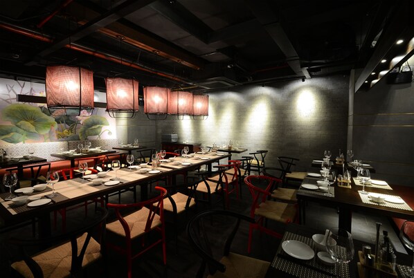 Un restaurante con varias mesas dispuestas para comer, con sillas rojas y una decoración de estilo moderno.