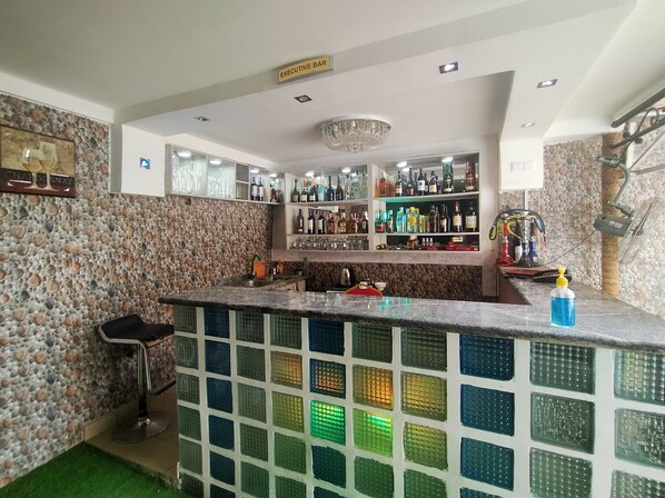 Una zona de bar con pared de piedra, un letrero que indica el bar ejecutivo, estantes con botellas y una barra.
