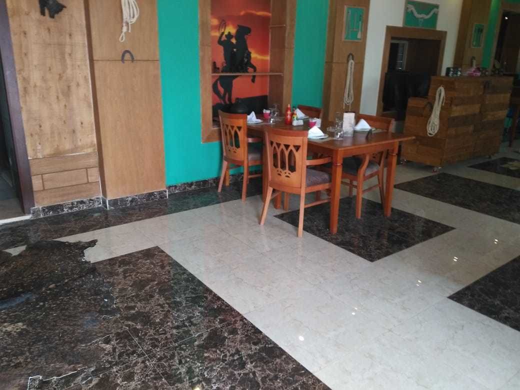A dining area with a wooden table and chairs, a tiled floor with a black and white pattern, and a wooden cabinet with a rope hanging from it.