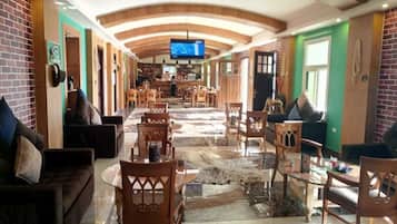 A hotel lobby with a long corridor, wooden furniture, a television, and a reception desk.