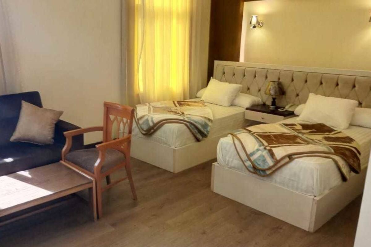A hotel room with two beds, a sofa, a chair, and a small table.