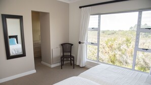 A bedroom with a large window, a chair, a bed, and a mirror. - 2 Sheerline (Knysna)
