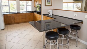 A kitchen with a central island, wooden cabinets, and a window with curtains. - 2 Sheerline (Knysna)