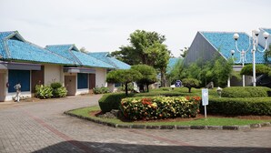 Un edificio con techos de tejas azules, un jardín ajardinado con diversas plantas y un cielo despejado.