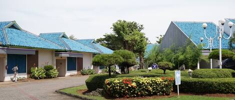 A building with blue-tiled roofs, a landscaped garden with various plants, and a clear sky.