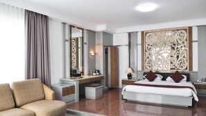 Una habitación de hotel moderna con sofá, escritorio, cama y un amplio espejo.