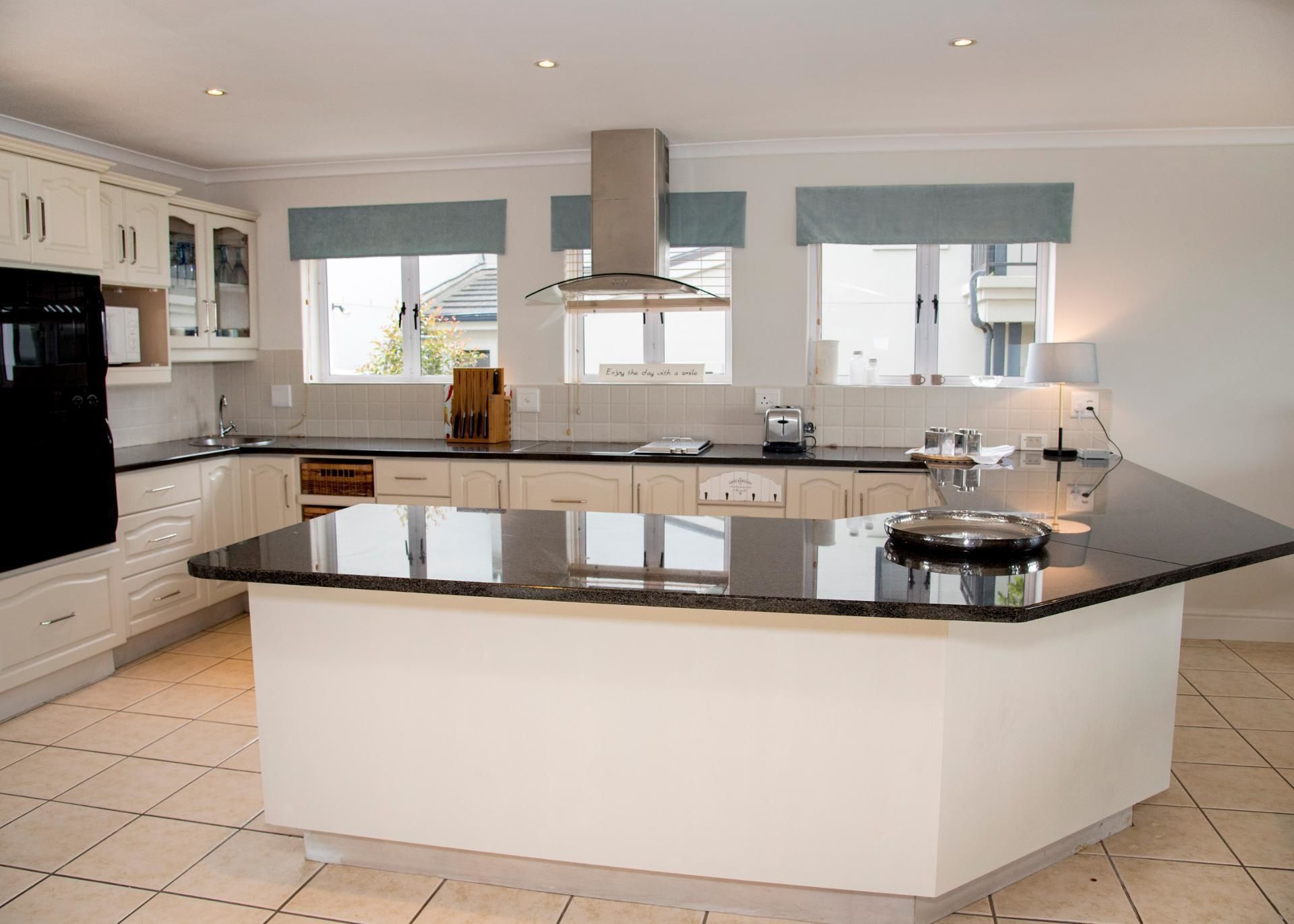 A modern kitchen with white cabinetry, a large island, and a black countertop.