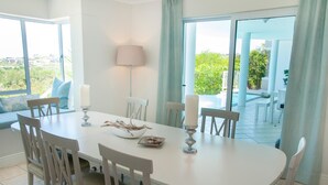 A dining area with a white table, four chairs, two candles, and a bowl of food. - 8 Sheerline (Knysna)