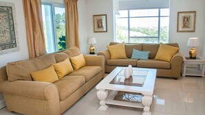A living room with two beige sofas, a white coffee table, and two lamps. - 8 Sheerline (Knysna)