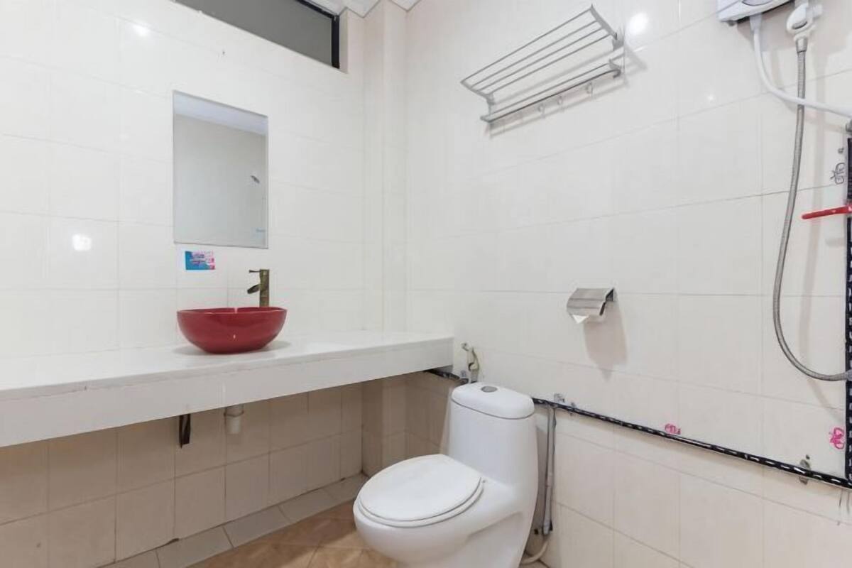 Une salle de bain avec un lavabo blanc, un receveur de douche rouge, des toilettes blanches et un espace douche.