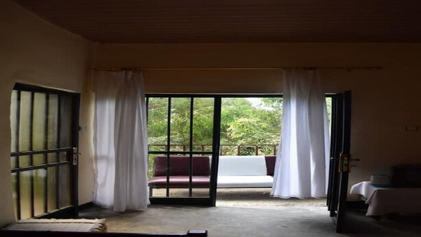 A room with a sliding glass door leading to a balcony with a red and white sofa.