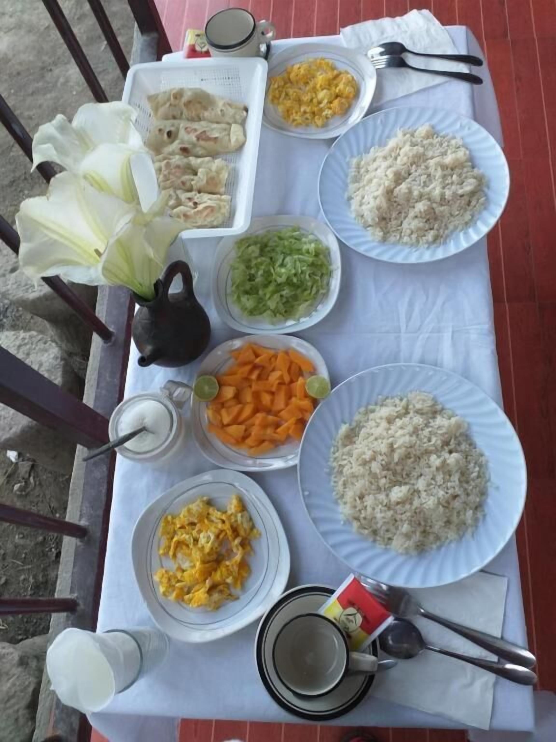 Una mesa servida con diversos platos, incluyendo arroz, huevos revueltos y verduras.