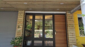 A multi-story building with a wooden deck, a garage door, and a potted plant. - Muguang Inn (Hengchun)