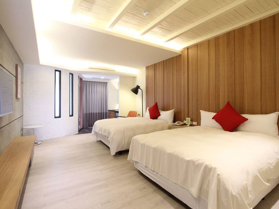 Habitación de hotel con dos camas, una pared de acento de madera, un televisor de pantalla plana y un banco.