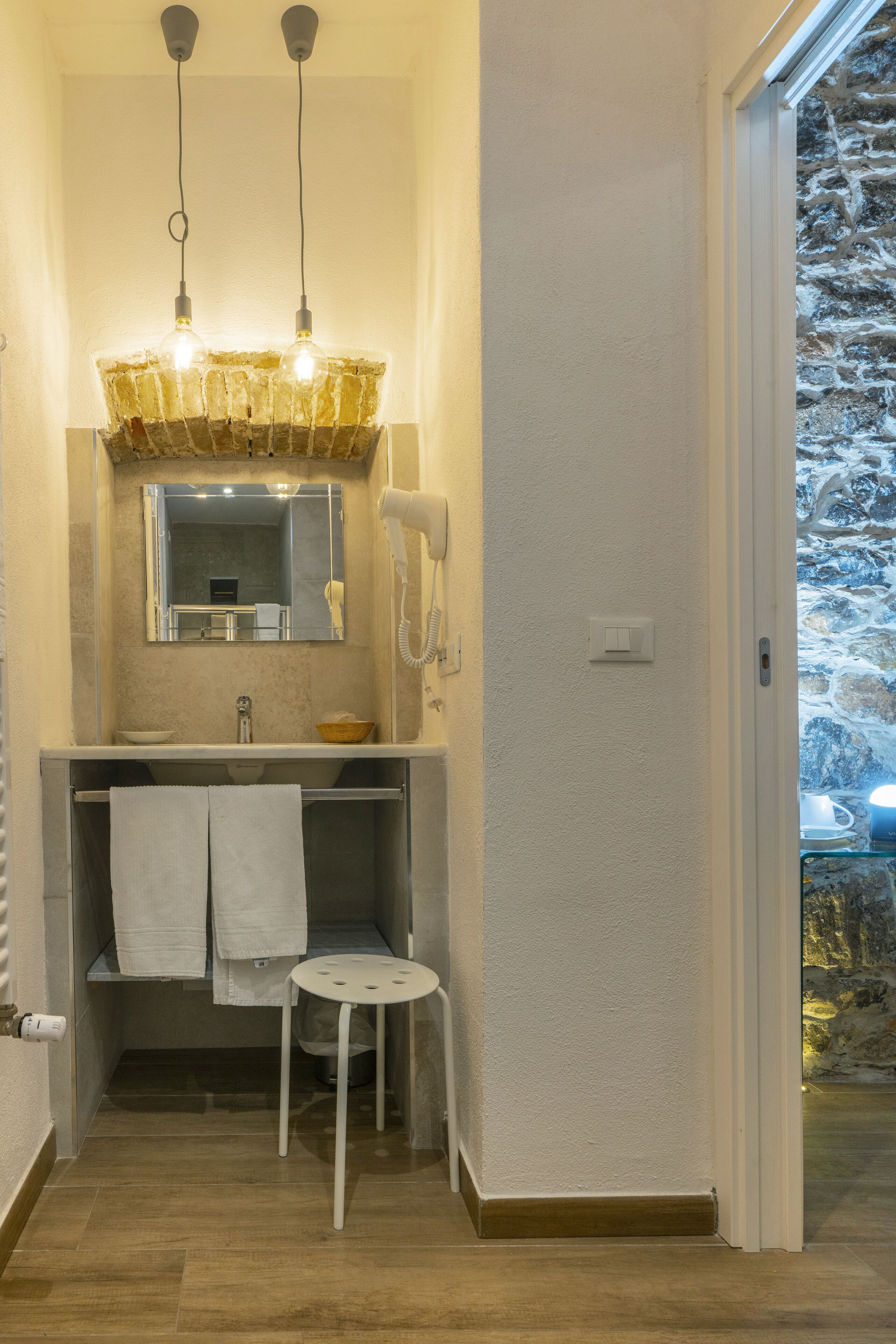 Baño con lavamanos, espejo, secador de pelo y dos luces colgantes.