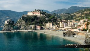 A coastal town with historic buildings, a prominent castle on a hill, and a beach.