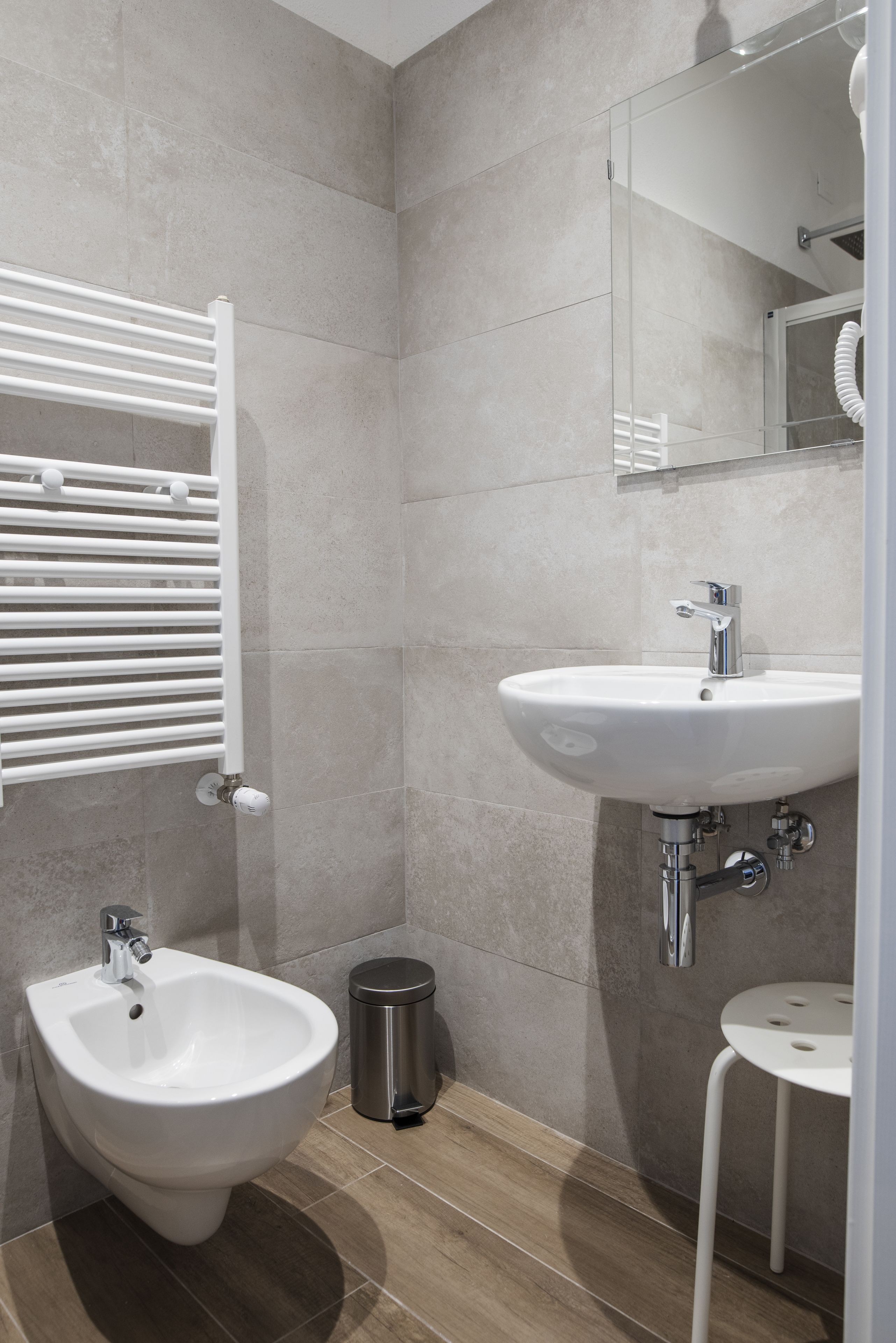 Une salle de bain moderne équipée d’un bidet, d’un lavabo et d’un porte-serviettes.