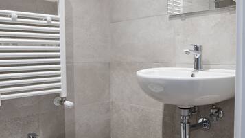 Une salle de bain moderne équipée d’un bidet, d’un lavabo et d’un porte-serviettes.
