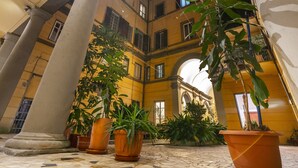 Un patio con suelo de baldosas, grandes columnas y plantas en macetas.