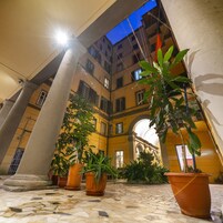 Un patio con suelo de baldosas, grandes columnas y plantas en macetas.