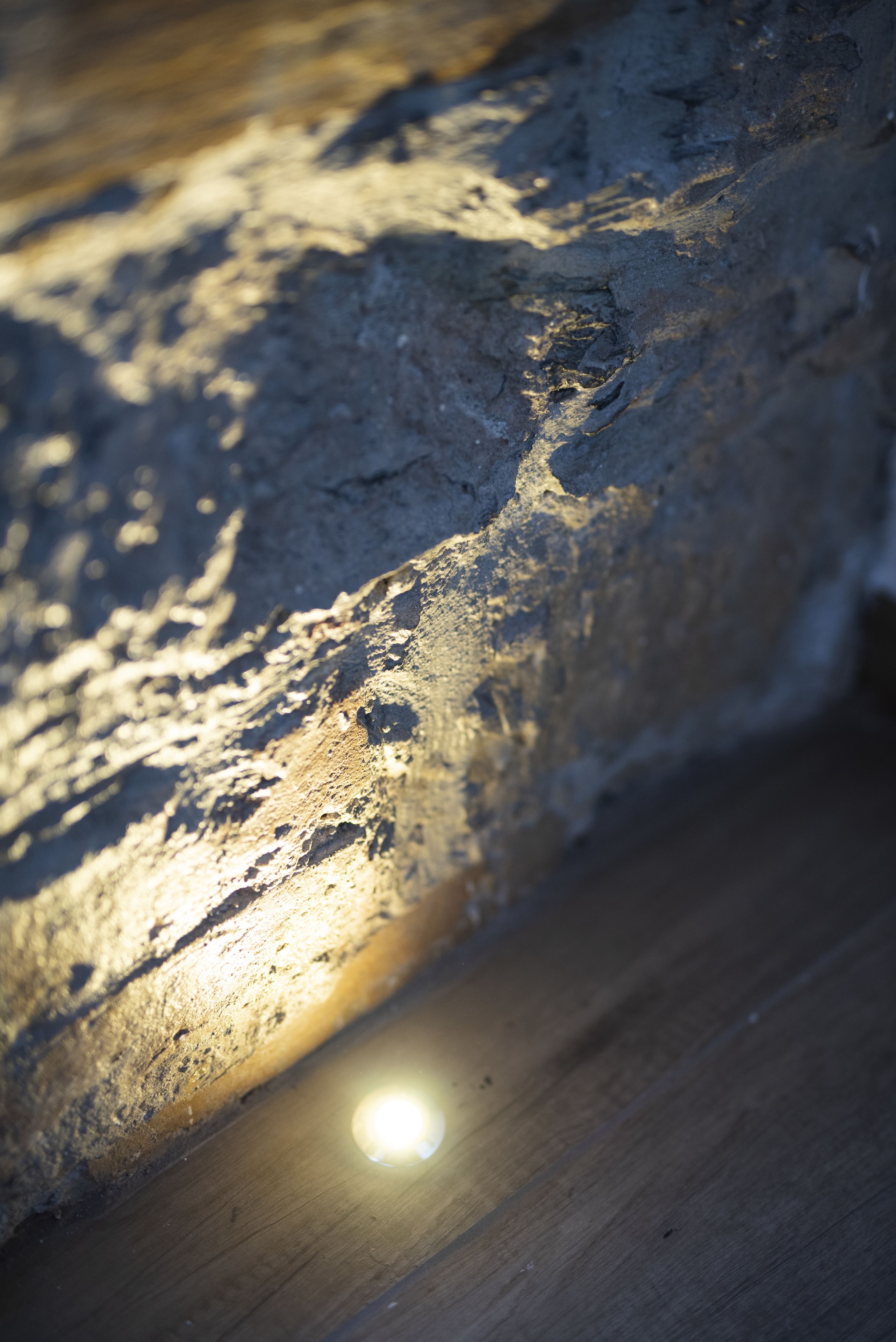 A close-up of a textured stone wall with sunlight casting shadows.
