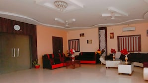 A spacious living room with a high ceiling, a large window, and a modern fireplace. - Hotel The Royal Buddha (Gaya)