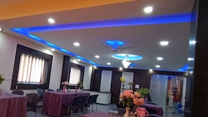 A conference room with tables, chairs, and a ceiling with blue lighting. - Hotel The Royal Buddha (Gaya)