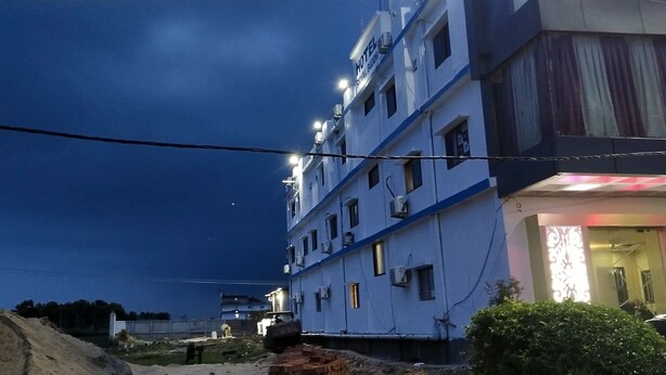 A multi-story hotel with a visible ground floor entrance, multiple windows, and air conditioning units. - Hotel The Royal Buddha (Gaya)
