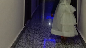 A hallway with a person in a white dress walking away from the camera. - Hotel The Royal Buddha (Gaya)