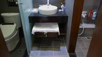 A compact bathroom with a white sink, a toilet, and a small storage basket.