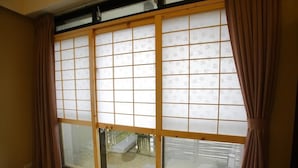 Habitació amb porta corredissa de shoji, terra de tatami i vista al jardí per la finestra.