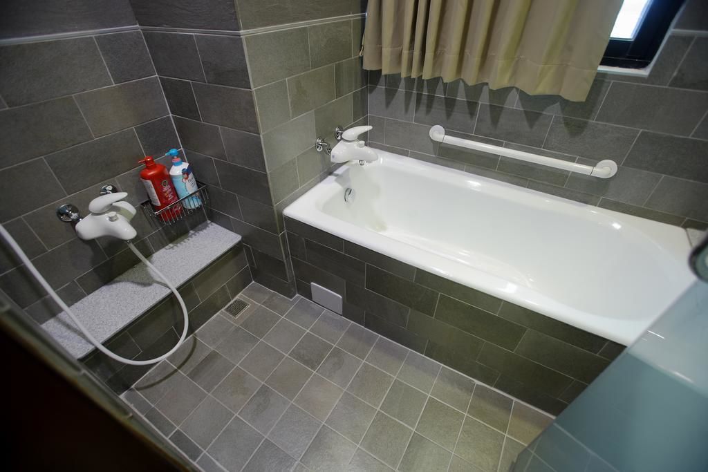 A bathroom with a bathtub, a shower, and a towel rack.