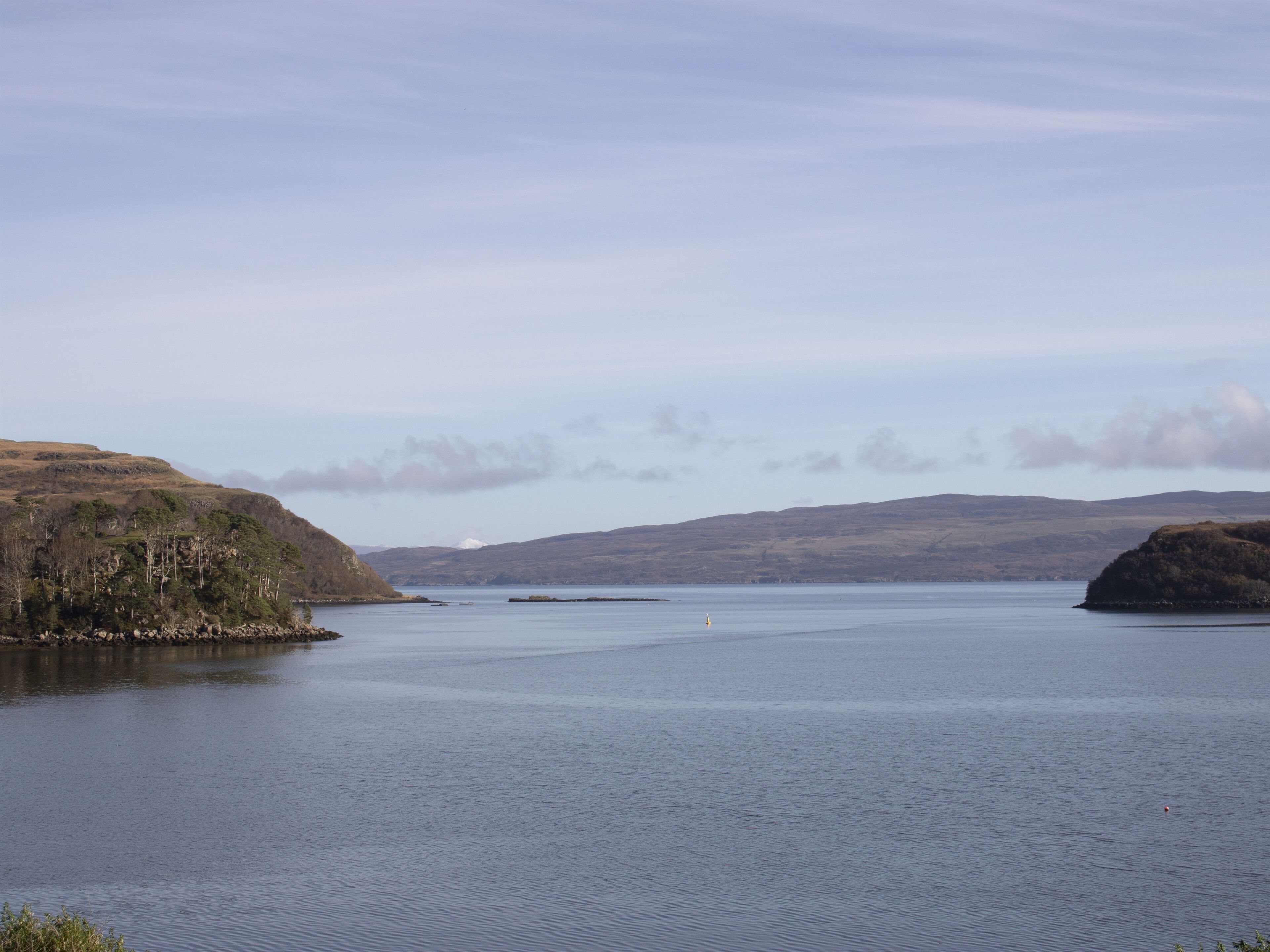 A calm lake with hills in the background and a clear sky.