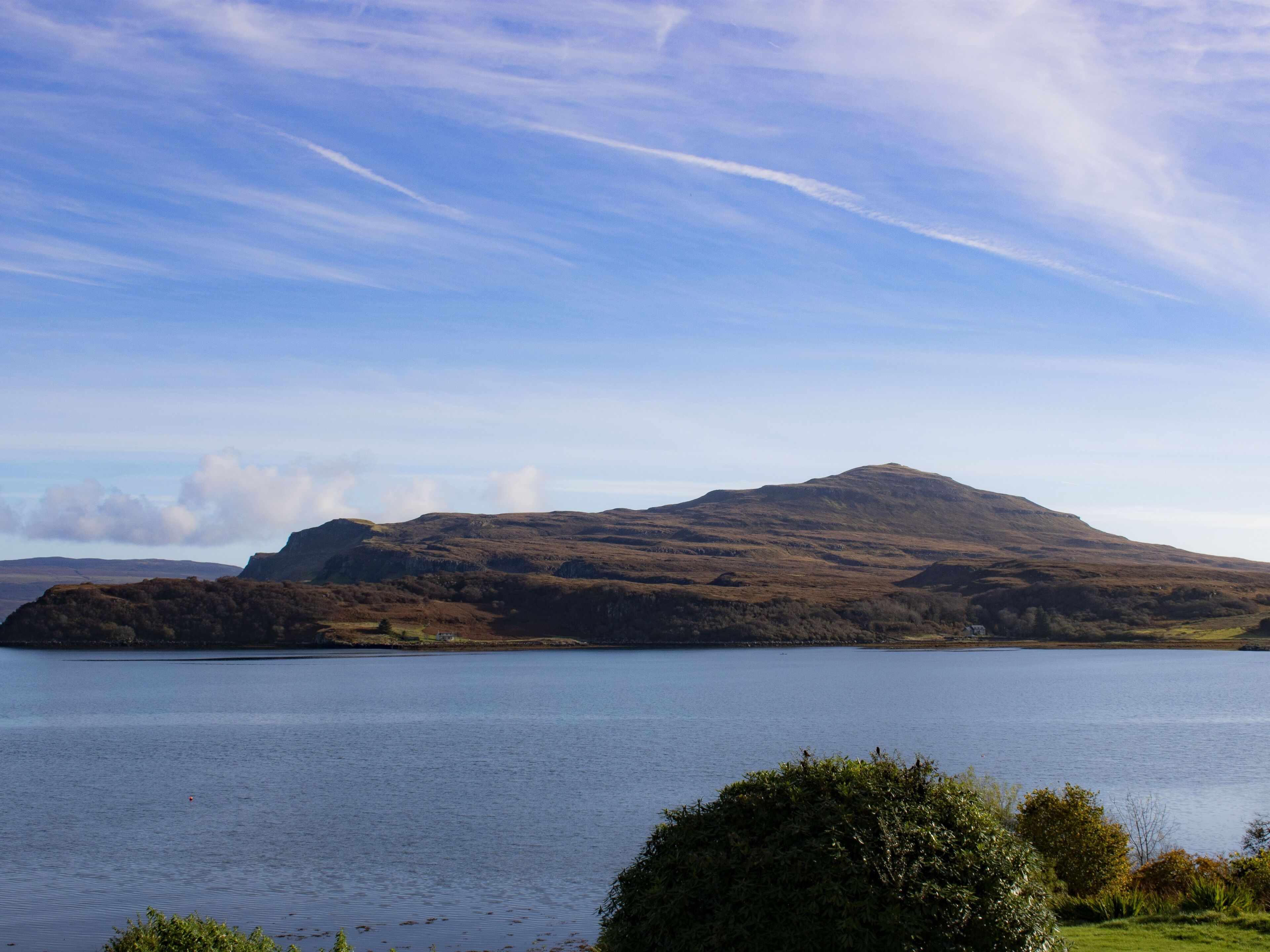 A mountainous landscape with a lake in the foreground and a clear sky.
