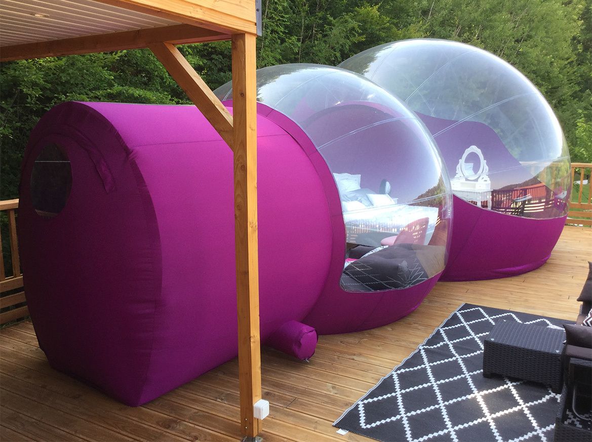 Transparent bubble pods on a wooden deck with a view of a building in the background.