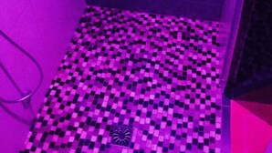 A bathroom with a checkered floor pattern and a shower area. - La Bulle Des Anges (Illoud)
