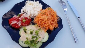 A plate with sliced cucumbers, carrots, and a white creamy substance, possibly a salad or dip, on a dark plate. - La Bulle Des Anges (Illoud)
