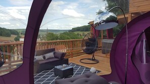 Un espace de détente extérieur accueillant, avec un canapé, un fauteuil et une table, offrant une vue sur un paysage pittoresque.