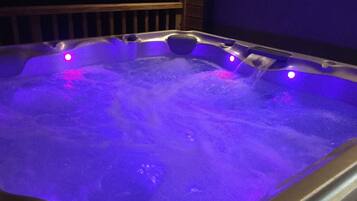 A hot tub with water jets and purple lighting.