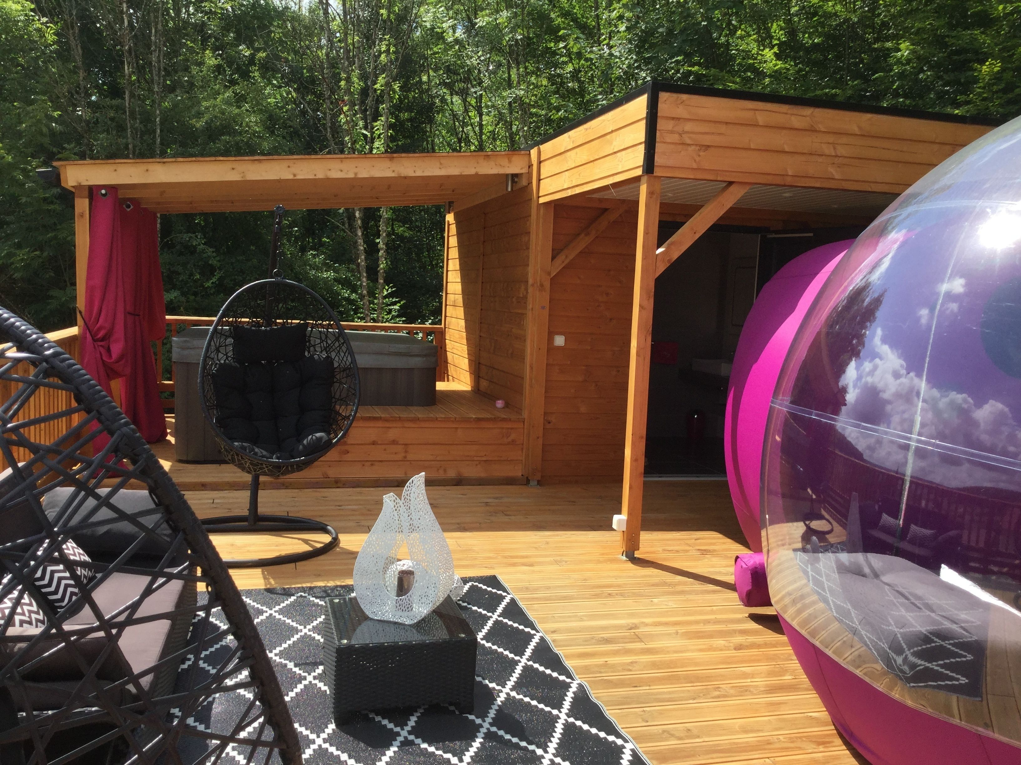 A wooden deck with a hanging chair, a small table, and a large spherical mirror.