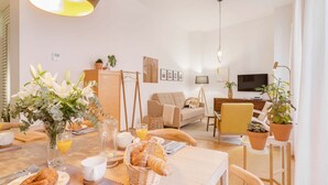 A modern living room with a sofa, coffee table, and dining area with breakfast items.