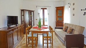 Un comedor con una mesa de madera, sillas y un televisor sobre un mueble.