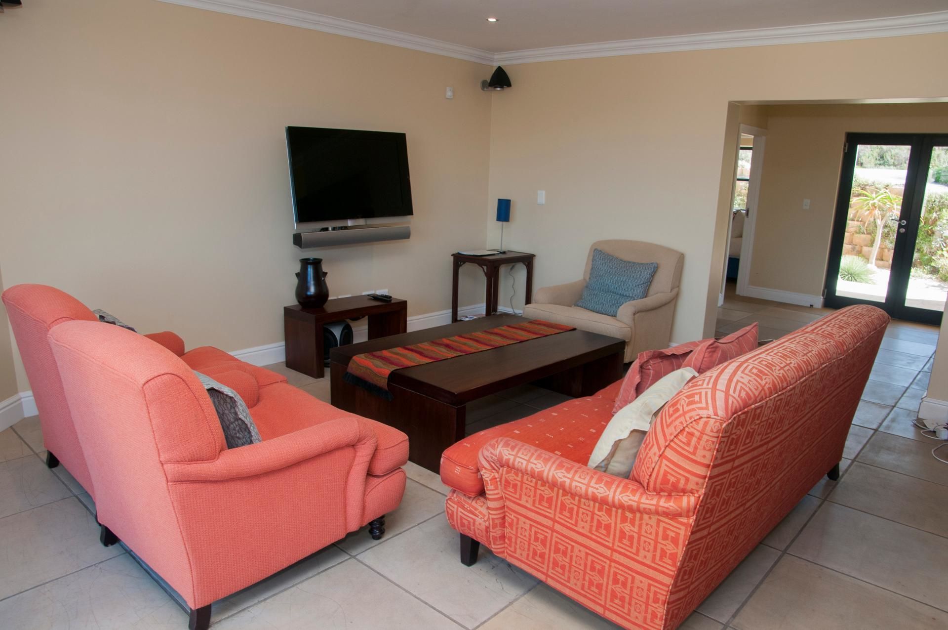 A living room with two orange sofas, a coffee table, a TV, and a chair.