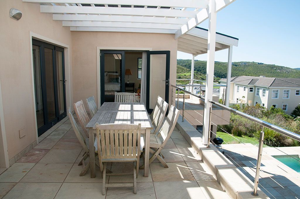 Un balcone con un tavolo e sedie in legno, una piscina e vista sulla campagna circostante.