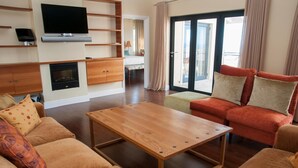 A modern living room with a wooden coffee table, beige sofas, and a red sofa with cushions. - 4 Spinnaker (Knysna)