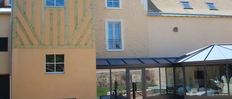 A courtyard with a glass-enclosed patio, a small seating area with chairs, and a stone planter.
