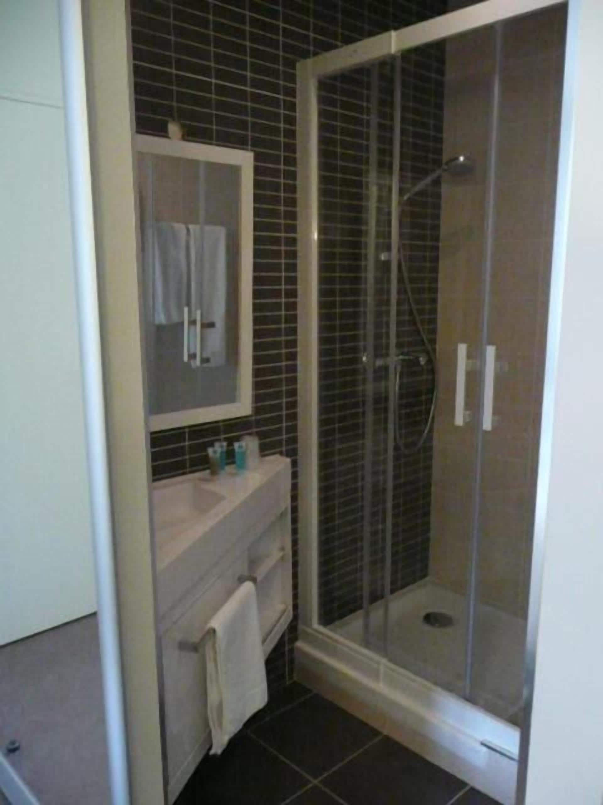 A bathroom with a glass-enclosed shower, a white sink, and a mirror above the sink.