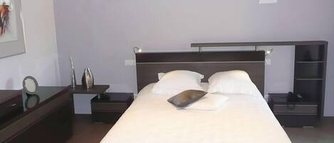 Un dormitorio ordenado con una cama grande, mesitas de noche, un aparador y un armario.