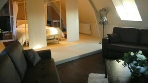 Een knus loft slaapkamer met een bed, een raam en een moderne lamp.