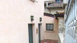 A narrow alleyway with a stone floor, a brick planter with greenery, and a metal gate. - Holideal Casa Lauretta (Tremosine)